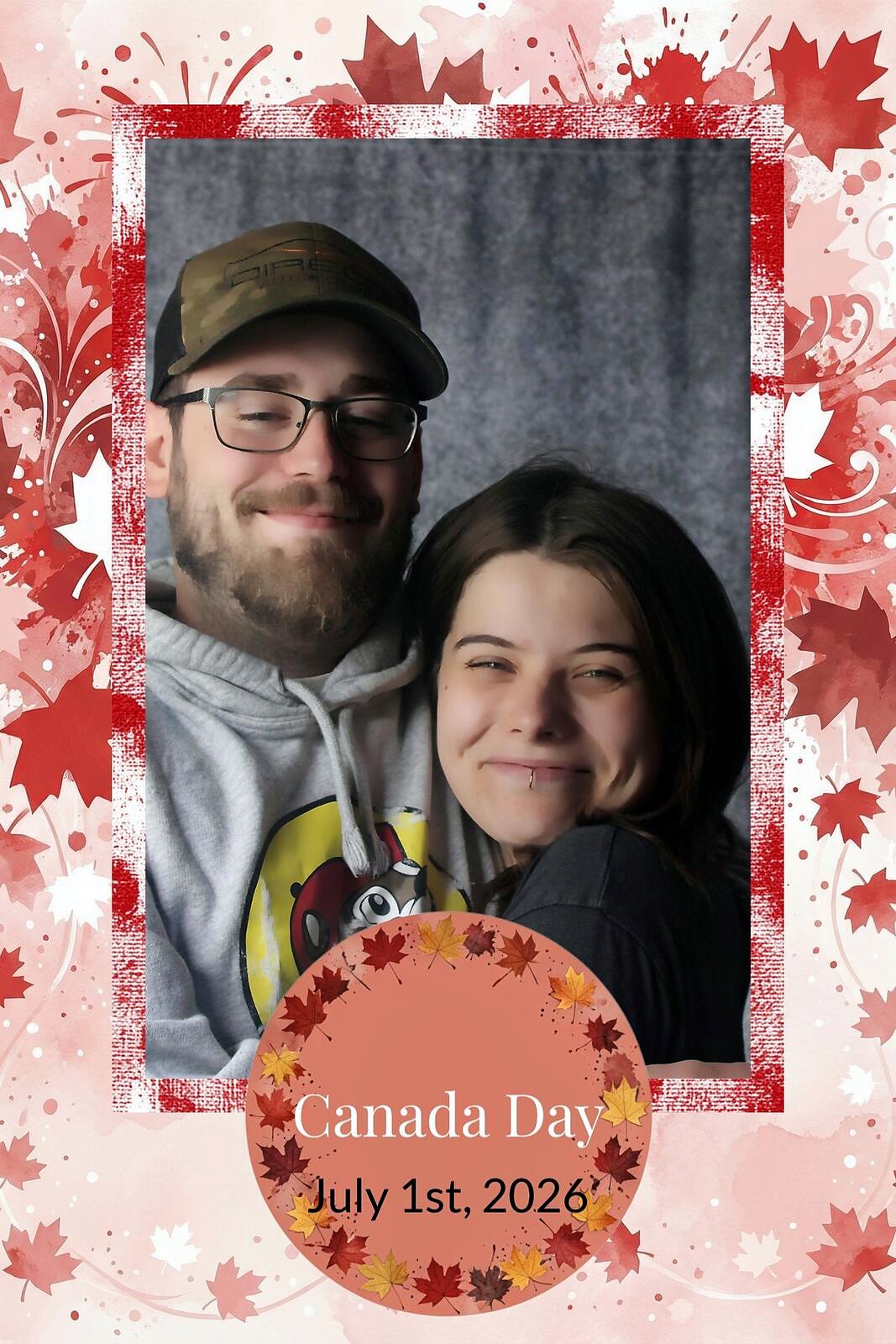 A couple in ball caps and hoodies, cheek to cheek, in the red maple leaf Canada Day overlay