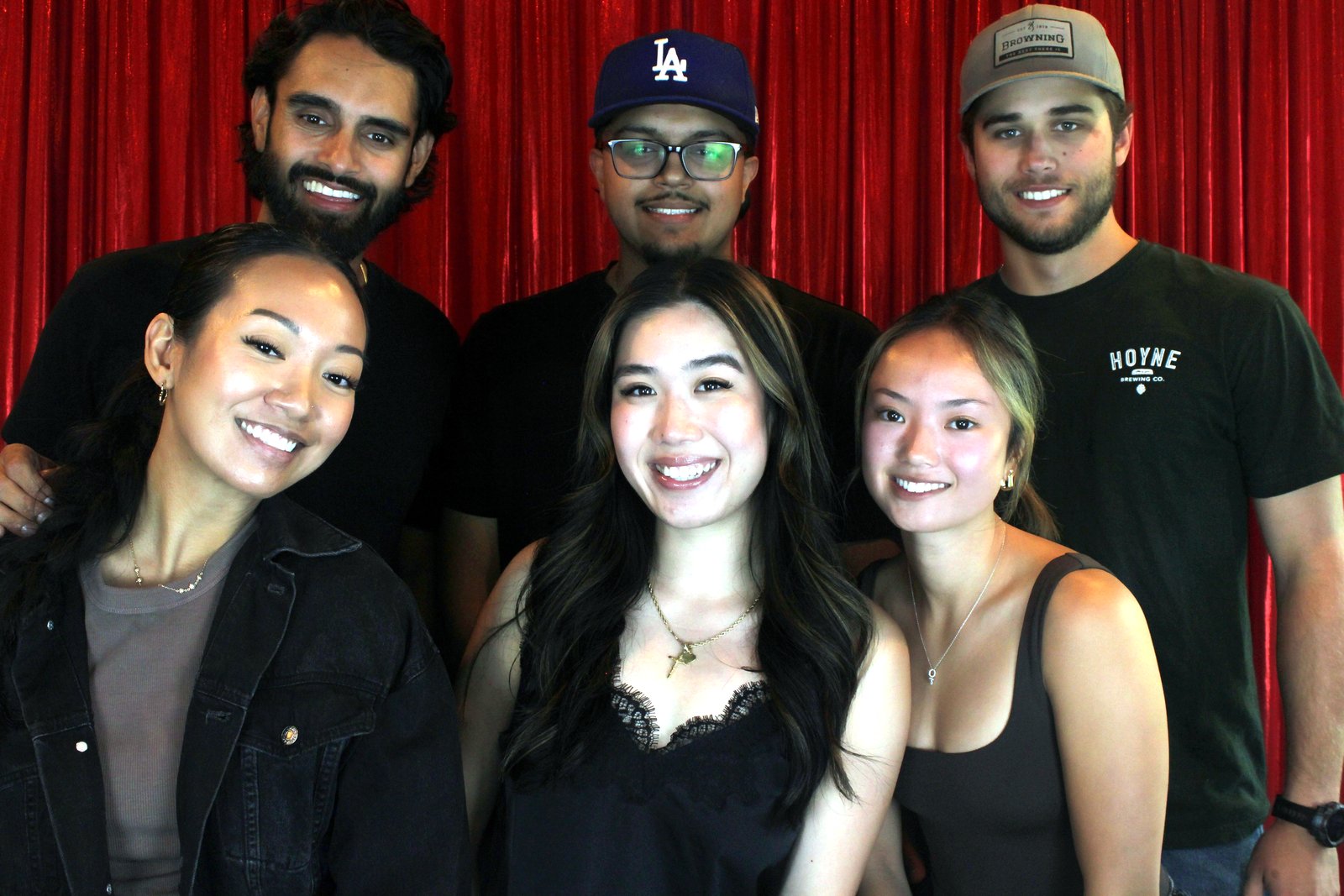 Six friends in a row in front of the red curtain at The Dudley's grand opening
