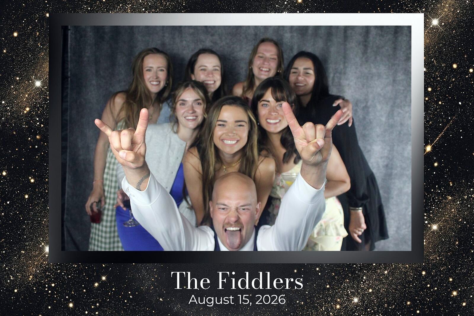 A wedding party of eight cheering in front of a starry backdrop on The Fiddlers overlay
